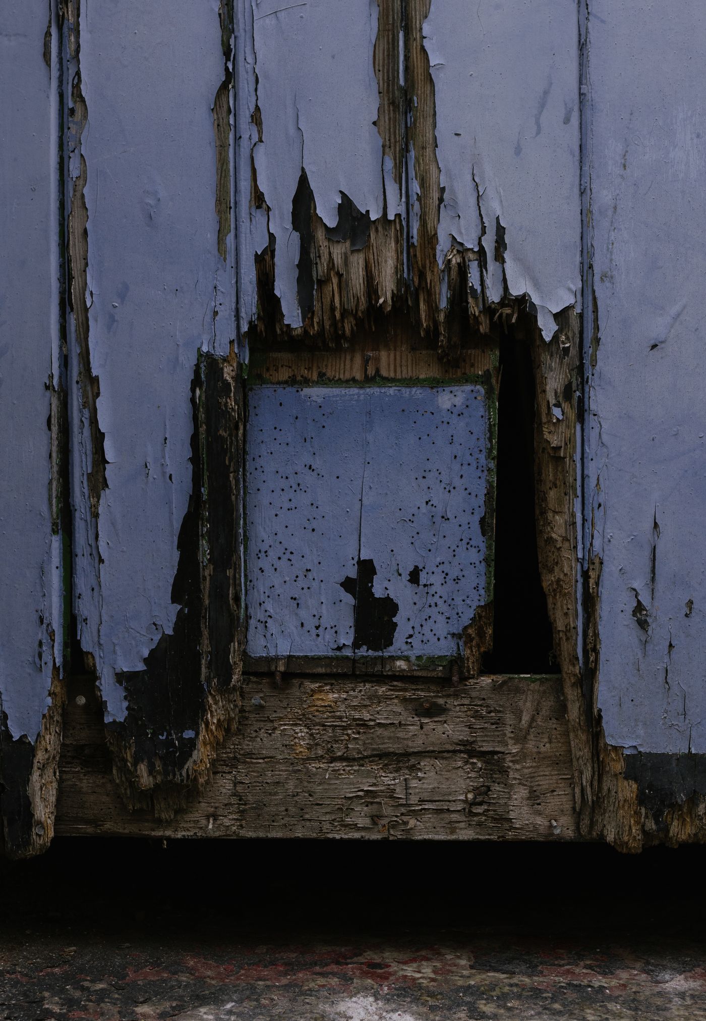 Weathered wooden door with peeling paint and damaged timber